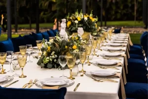 Mesa de jantar sofisticada com arranjos florais e detalhes elegantes em um ambiente ao ar livre.