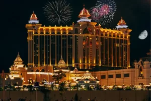 Fachada iluminada de hotel icônico com fogos de artifício ao fundo, representando sofisticação e celebração cultural.